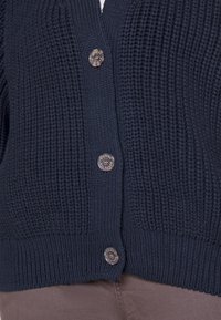 Cardigan lavorato a maglia blu navy con un motivo testurizzato, dotato di sei bottoni metallici con marchio inciso al centro e in basso.