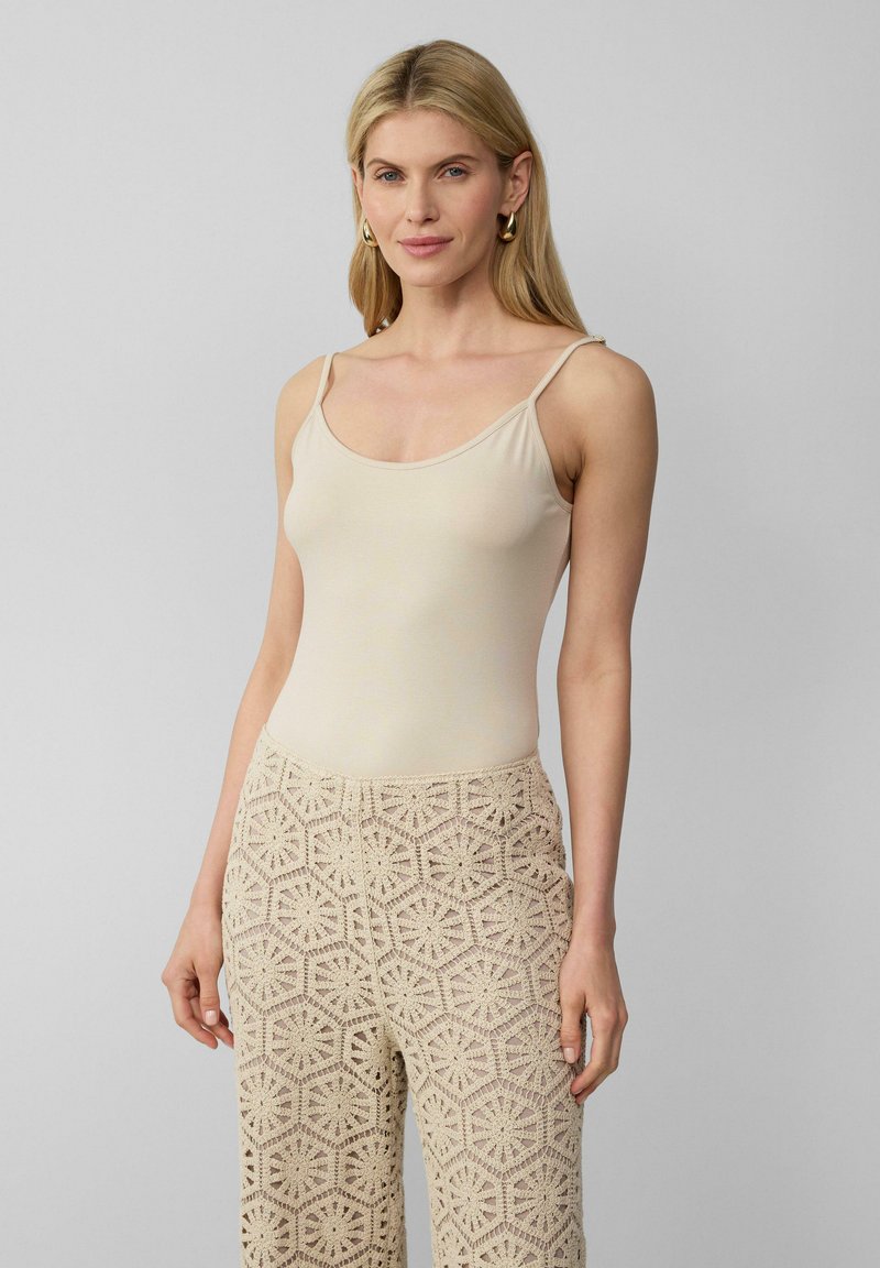 Beige, aansluitende tanktop met dunne schouderbandjes, gecombineerd met beige gehaakte broek met hexagonale bloemenpatronen en een losse pasvorm.
