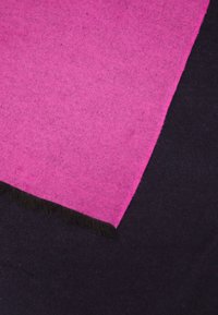 Écharpe rose et noire en tissu doux, présentant un design à blocs de couleur contrastants avec des bords frangés.