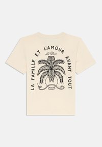 Cremfarbendes T-Shirt mit kurzen Ärmeln, das auf der Rückseite eine schwarze Grafik einer Palme und dekorativen Text zeigt.