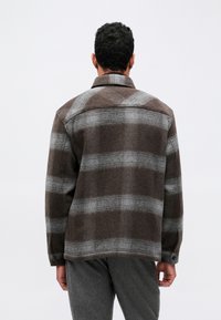 Καφέ και γκρίζο καρό jacket από μάλλινο ύφασμα με γιακά και κουμπωτές μανσέτες, διαθέτοντας χαλαρή εφαρμογή και απαλή υφή.