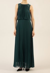 Robe maxi en vert profond, avec un tissu plissé, un design sans manches et un corsage à couches. Texture douce, avec une silhouette fluide.