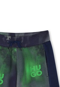 Jogging en marque Hugo avec un design abstrait vert et gris foncé, une taille et un cordon de serrage bleu marine, et des poches latérales.