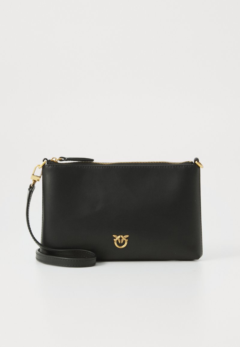 Svart skinnkoffert med gullglidelås og logo. Har avtakbar stropp og glatt tekstur. Rektangulær form med minimalistisk design.