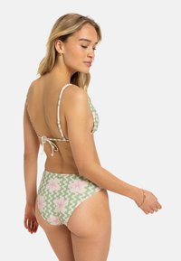 Bikini set s zeleno-bielym cik-cak vzorom a ružovými kvetinovými akcentmi, s nastaviteľnými ramienkami a uzatváraním na šnúrku.