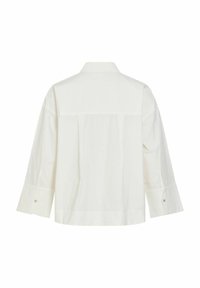 Chemise blanche à manches longues vue de dos avec un col droit et des poignets boutonnés sur un fond uni.