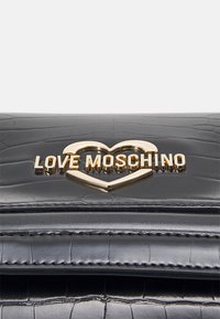 Zwart gestructureerde leren handtas met een gouden metalen hart en het "LOVE MOSCHINO"-logo op de voorste klep.