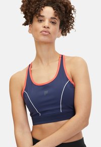 Top corto atlético de color azul marino con detalles en rosa, que cuenta con un escote redondo, diseño tipo racerback y costuras en blanco que contrastan. Logo en la parte delantera.