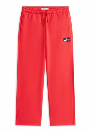 Pantalon de survêtement rouge à coupe décontractée avec taille élastique, cordon de serrage, poches latérales et écusson du logo Tommy Hilfiger sur la partie supérieure de la cuisse gauche.