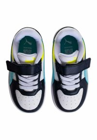 Zapatillas en blanco y negro con acentos en turquesa y amarillo. Cuenta con una correa de velcro y cordones, puntera redondeada y diseño perforado en la caja de los dedos.