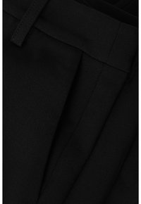 Pantaloni in tessuto nero con texture liscia, dotati di un fronte piatto e pieghe visibili, cuciture dettagliate e una vestibilità sartoriale.