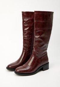 Bottes burgundy à hauteur de genou avec un motif crocodile embossé et brillant, bout carré et talon bloc ; fermeture éclair sur le côté pour un enfilage facile.