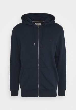 Sudadera con capucha azul marino con cremallera, hecha de material suave, con capucha ajustable con cordón, bolsillos delanteros, puños acanalados y un pequeño logo en el pecho.
