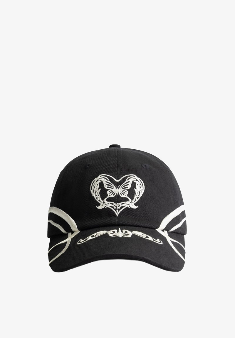 Zwarte pet met witte decoratieve borduursels met een hart- en vlindermotief. Aangevuld met witte strepen langs de klep. Gemaakt van katoen.