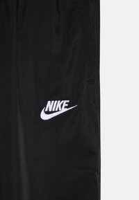 Melnas sporta bikses, izgatavotas no viegla auduma. Ar baltu izšūtu Nike logo. Gluda tekstūra ar sānu vīlēm.