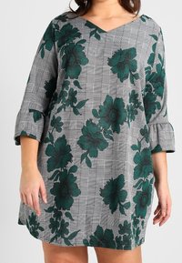 Sukienka podkreślająca V w kolorze szarym z czarnym wzorem w kratkę, z dużymi ciemnozielonymi nadrukami kwiatowymi oraz rękawami o długości ¾ z falbankami.