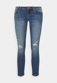 Jeans ajustados de denim azul con detalles desgastados, que incluyen rasgaduras, bolsillos estándar y cierre con botón. Diseño clásico de cinco bolsillos.