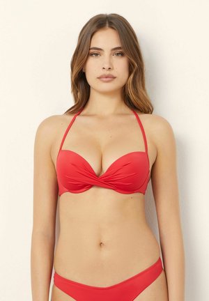 Ensemble de bikini rouge avec un design twisté sur le haut et des fines bretelles. Tissu lisse et extensible avec une couverture minimale au bas.