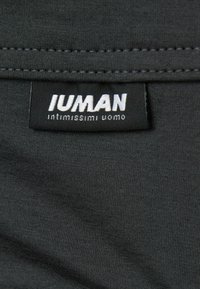 Donkergrijze stof met een gladde, zachte textuur heeft een zwart etiket met de tekst "IUMAN" en "intimissimi uomo" in witte letters.