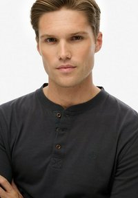 Czarna longsleeve koszula henley z zapięciem na guziki i haftowanym logo. Miękka tkanina o gładkiej teksturze oraz ściągacze mankietów.