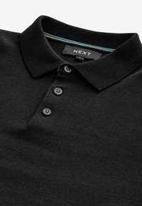 Camisa polo negra hecha de tejido texturizado, con cuello tipo polo, tapeta de tres botones y rayas coloridas en el interior del cuello.