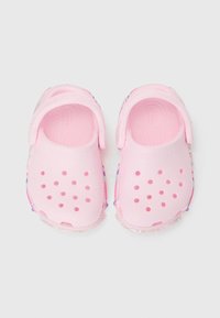 Pink clogs with perforated design for breathability, flexible material, and a transparent glittery sole accent. No visible hardware.