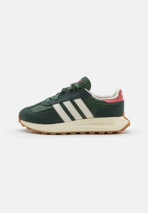 Ciemnozielony sneaker Adidas z białymi paskami, kremową wyściełaną podeszwą, gumową podeszwą zewnętrzną, różową zakładką na pięcie i zielonymi sznurowadłami na białym tle.