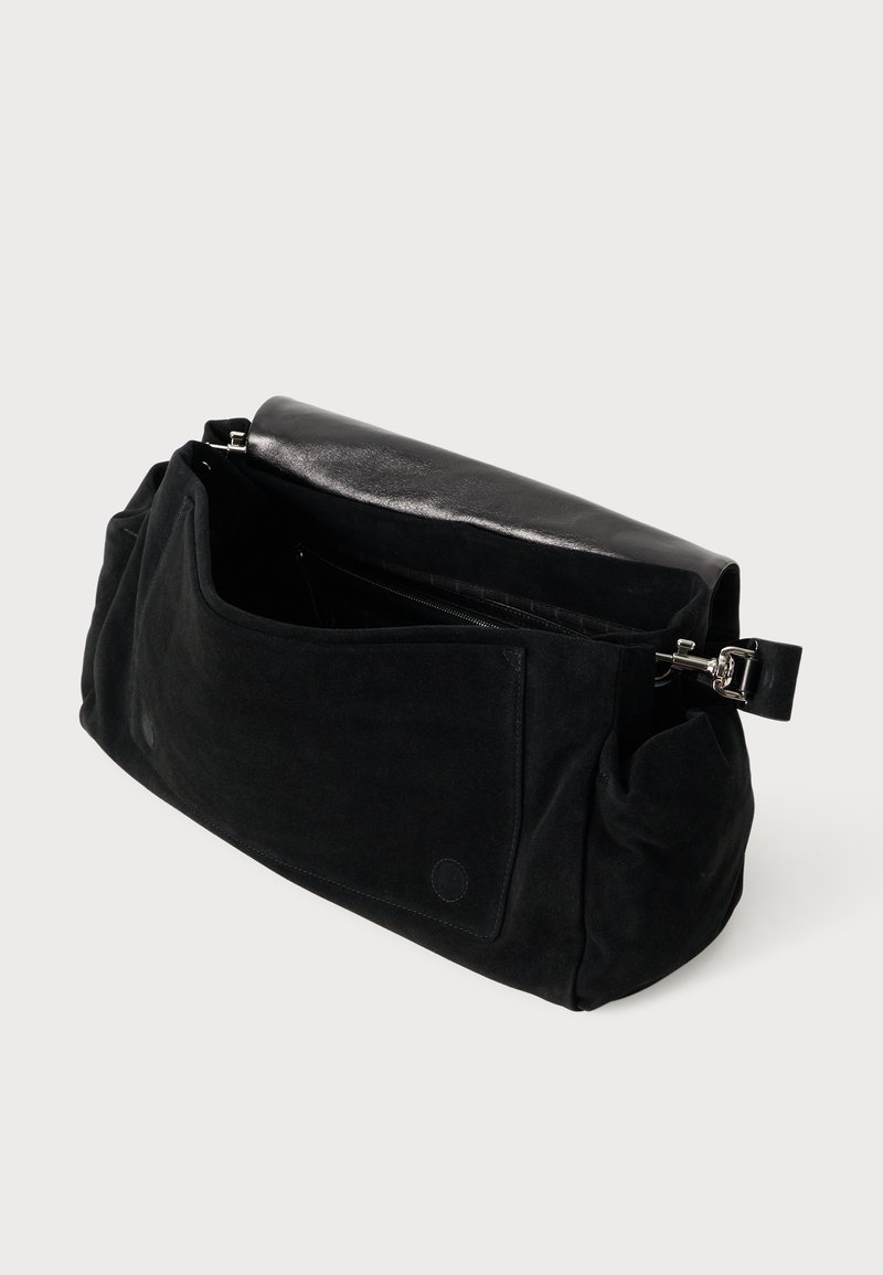 Schwarze Wildleder-Handtasche mit einer glänzenden schwarzen Lederklappe, einer Fronttasche und silbernen Beschlägen. Weiche Textur und geräumiges Innendesign.