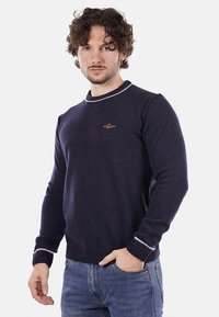 Maglione lavorato a maglia blu navy con collo rotondo, polsini e orlo a costine, caratterizzato da accenti grigio chiaro e un piccolo logo ricamato sul petto.