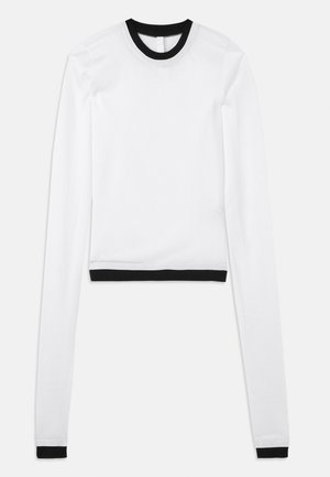 Hvit crop-top med lange ermer, svart ribbestrikket rund hals og matchende svarte detaljer ved mansjettene. Glatt, elastisk stoff.