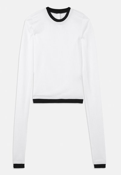 Crop top blanc à manches longues avec un col rond côtelé noir et des accents noirs assortis aux poignets. Tissu lisse et extensible.