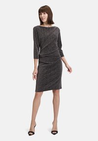Abito in maglia grigio scuro con leggeri filamenti metallici. Presenta un collo a barca, maniche a tre quarti e dettagli arricciati in vita.