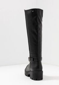 Černé vysoké boty vyrobené z hladké syntetické kůže, s detailem přezky na kotníku a texturovanou, masivní podešví.