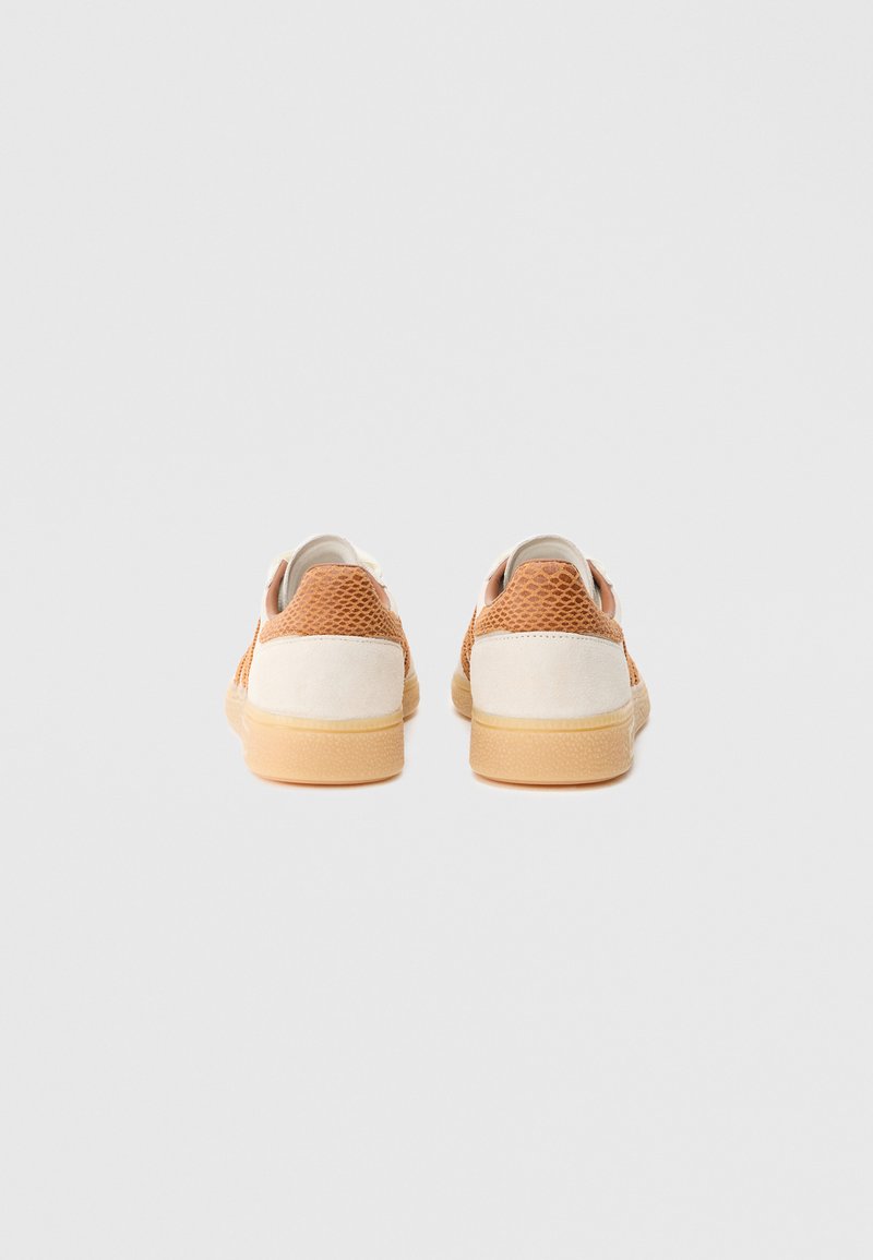 Scarpe da ginnastica con una combinazione di colori beige e crema, tomaia in mesh strutturato, dettagli in suede e suola in gomma. Accenti cuciti visibili.