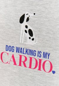 Šedé tričko s výšivkou černo-bílého designu psa a textem "VENČENÍ PSŮ JE MOJE KARDIO" v modré a růžové barvě.