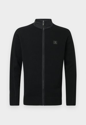 Černý svetr na zip s vysokým límcem, žebrovanými manžetami a lemem, jemnou texturou a malou logovou nášivkou na levé straně hrudi.