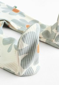 Pernă pentru gât dintr-un material moale, cu o textur�ă canelată, având un model floral abstract în nuanțe de albastru deschis, crem și portocaliu. Design ergonomic cu margini rotunjite.