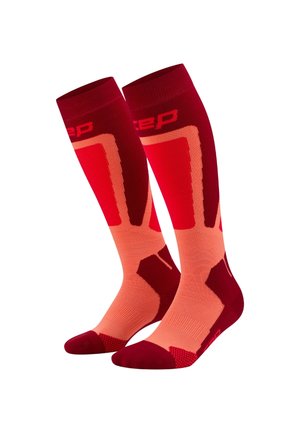 Calze compressive in rosso e pesca chiaro, design fino al ginocchio con motivi testurizzati, punta ammortizzata e tallone rinforzato. Logo visibile nella parte superiore.