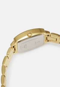 Gold-tone wristwatch with a rectangular case, metal band, and a prominent crown. Smooth texture and minimalist design with a silver back.
