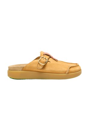 Zueco de cuero tipo slip-on color beige con hebilla lateral y suela plana de goma, diseñado para uso casual.