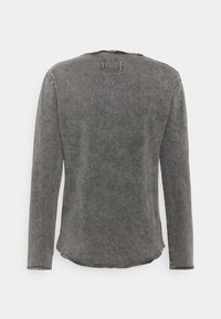 Szara koszula z długim rękawem o swobodnym kroju, z okrągłym dekoltem, niedokończonym dołem i subtelną fakturą oraz kwadratowym przeszyciem z tyłu.