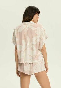 Casualny zestaw składający się z dwóch części, zawierający krótki rękaw t-shirt oraz szorty. Wykonany z miękkiego materiału z różowym tłem i dużym białym wzorem kwiatowym.