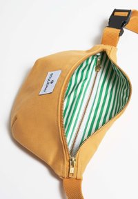 Borsa in tela gialla con un interno a righe verdi e bianche. Presenta una cerniera dorata e una tracolla arancione removibile. L'etichetta recita "SOULEWAY."