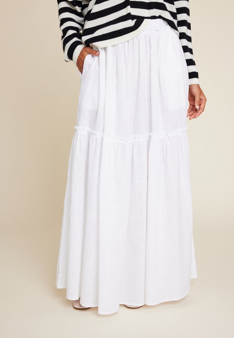 Hvit, lagdelt maxi-skjørt laget av lett stoff, med elastisk liv og sidelommer. Bært med en topp med svart og hvite striper.