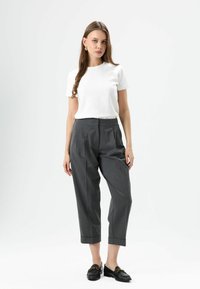 White short-sleeve t-shirt paired with high-waisted, tapered gray trousers, featuring a folded hem and black loafers with gold hardware accents.
