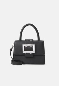 Sac à main noir avec une poignée supérieure, grande boucle en métal argenté sur le rabat avant, et une sangle détachable pour le poignet sur fond blanc.