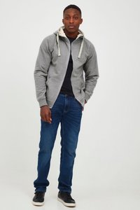 Grå lynlås-hættetrøje med cremefarvet indvendig foring og kontrastfarvede snore, kombineret med mørkeblå jeans og sorte sneakers.