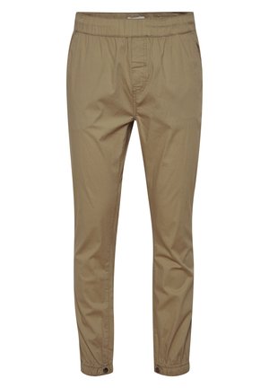 Light beige, tapered pants with an elastic waistband and button closures at ankles. Made of a smooth material with a minimal design.