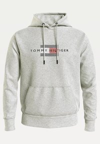 Jasnoszara bluza z kapturem, z przednią kieszenią oraz czarnym i czerwonym logo i napisem Tommy Hilfiger na piersi.