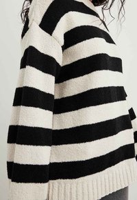 Schwarz-weißer gestreifter Pullover mit strukturierter Oberfläche, oversize Passform und geripptem Saum. Besitzt breite horizontale Streifen in kontrastierenden Farben.